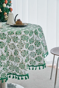 Detail of round tablecloth featuring pine needle print and green tassel fringe edging