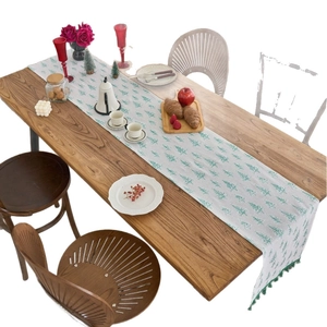 Green pine tree print Christmas table runner with tassels on a rustic wooden dining table
