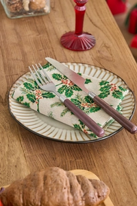 Close-up of stainless steel cutlery with wood handles on a green maple leaf napkin