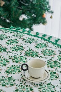 Close-up of Christmas tablecloth with green pine branch print and elegant fringe edges