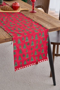 Detail of red Christmas table runner with green tree patterns and small red pom-poms