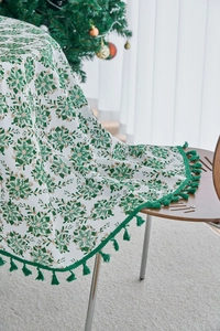 Detailed close-up of pine branch print tablecloth with green fringe trim for Christmas