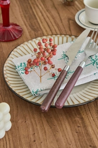 Close-up of retro stainless steel cutlery set with wood-texture handles on green leaf napkin