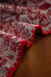 Detail of red vintage floral jacquard tablecloth with scalloped embroidered edges