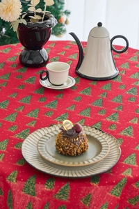 Detail of red Christmas tablecloth with pine tree prints and golden dots on a round table