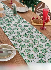 Table runner with green and white floral patterns on a wooden table with decor