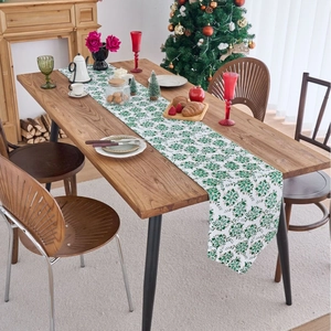 Christmas green table runner with gold leaf patterns on a rustic wooden dining table