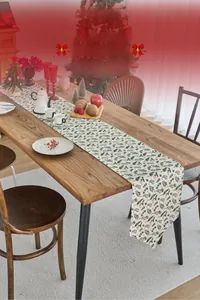Detailed close-up of a Christmas table runner with green pine needles and red berries