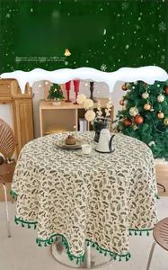 Detail of Christmas round tablecloth with green pine needles and red berry patterns