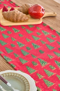 Detail view of red Christmas table runner with green trees on a wooden dining table