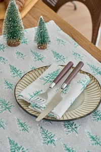 Close-up of linen fabric texture with green Christmas tree print and rustic table setting