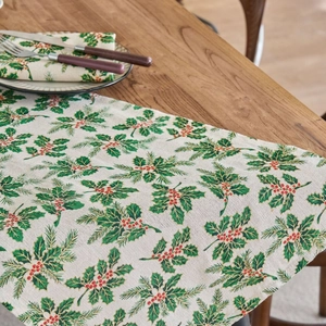 Christmas table runner with holly leaves and red berries on a rustic wooden table