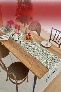 Dettaglio del runner da tavola natalizio con nappe verdi e motivi di agrifoglio e bacche