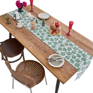 Elegant Christmas green table runner with golden foil floral pattern on a dark wooden table