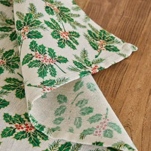 Christmas napkin with green holly leaves and red berry print on cream linen fabric