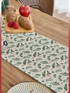 Detailed Christmas table runner with pine needles, red berries on beige linen texture