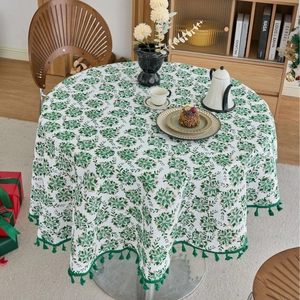 Round white tablecloth with green pine needle floral print and festive tassel trim