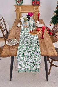 Detailed view of white textured Christmas table runner with green leaves and gold vines