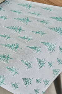 Detail of green Christmas tree pattern on linen texture fabric with snowy gold print