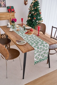 Close-up of green botanical Christmas table runner with tassels on a rustic wooden table