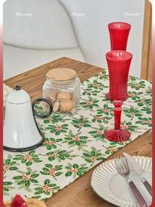 Detail of Christmas table runner with green holly leaves and red berry festive prints