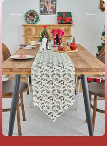 Detail of Christmas table runner with pine needles and red berries on beige fabric