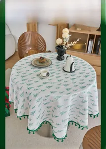 Detailed view of round Christmas tablecloth with pine tree prints and green tassel edges