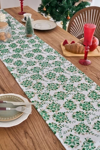 Detail of Christmas table runner with green floral prints and gold foil on wooden table