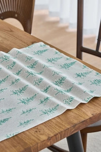 Close-up of a rustic linen table runner with green Christmas tree patterns on beige fabric