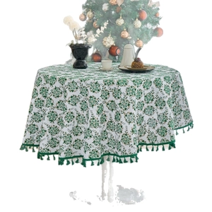 Round Christmas tablecloth with green pine print and tassel fringe on a set table
