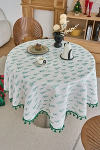Detail of pine tree print on round Christmas tablecloth with dark green tassel fringe trim