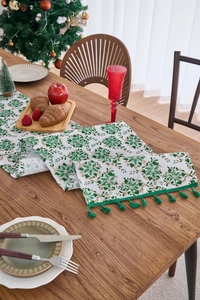 Close-up of beige Christmas table runner with green leaves and gold berry printing