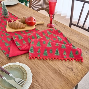 Festive red Christmas table runner with green gold tree prints and small red pom poms