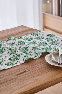 Detailed texture of green and gold leaf print on white cotton-linen table runner