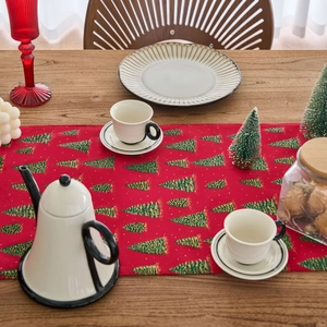 Red Christmas table runner featuring green and gold tree patterns on a wooden table