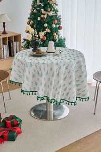Detailed view of pine tree printed tablecloth with green tassel edges and cotton texture