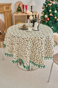 Detail of round Christmas tablecloth with pine needle prints and green tassel edges