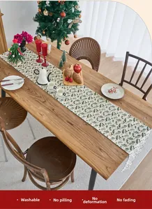 Detail of Christmas table runner with pine needles and red berries on a wooden table