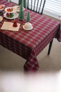 Close-up of thick red plaid tablecloth with festive Christmas table setting decor