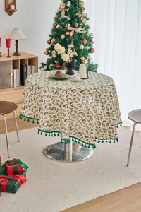 Detailed close-up of pine branch print round tablecloth with green tassels for Christmas