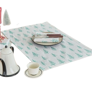 Christmas dinner napkins with green pine tree patterns on white linen fabric table setting
