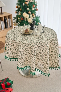 Close-up of pine needle pattern on round Christmas tablecloth with festive green tassels