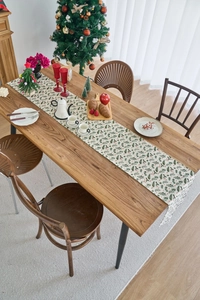 Christmas table runner with pine needles and red berries patterns on wooden table