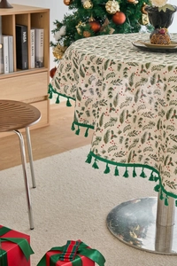 Detailed view of round Christmas tablecloth with pine needle print and green tassels