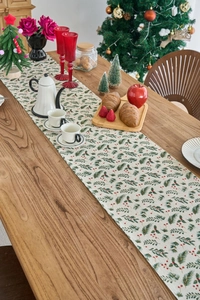 Detail of linen Christmas table runner featuring pine needles and red berries print