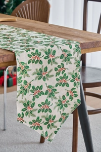 Detailed view of Christmas table runner with holly leaves and red berries on wooden table