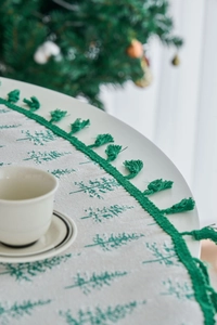 Detail of Christmas tablecloth with green pine tree print and fringe tassels