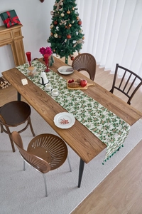 Detailed view of Christmas holly leaf print table runner with green pom pom tassel fringe