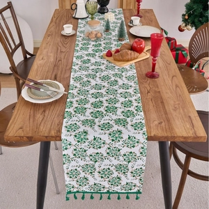 Green floral table runner with tassels on wooden table for elegant Christmas dining decoration