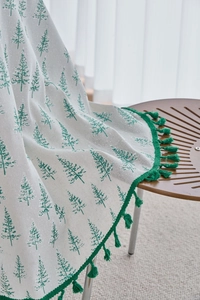 Close-up of pine branch pattern on cream cotton linen tablecloth with green tassels
